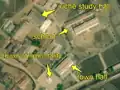 2/7 Another city centre regrouping a school (amenity=school), characterized by two long buildings (building=school) with a large courtyard in front (cf. Schools, a juche study hall (amenity=community_centre), with its specific shape, the immortality tower (historic=memorial), with its shadow on the ground, and the city hall (amenity=townhall) (Maxar satellite imagery).
