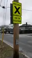 two traffic signs complimented by give way road markings. the first sign is large and florescent, saying, "stop for pedestrians," and the second sign is small and white, reading "caution: vehicles not required to stop."