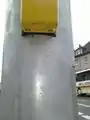 This photo shows the bottom of a button of a set of traffic signals with an arrow to indicate the direction of crossing for blind persons.